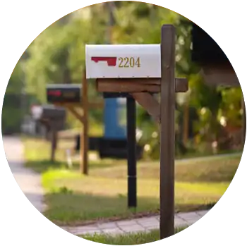 Multiple mailboxes line a suburban street. A white mailbox with a red handle is in focus.