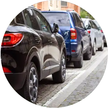 A crowded row of cars are parked the street in close proximity to one another.